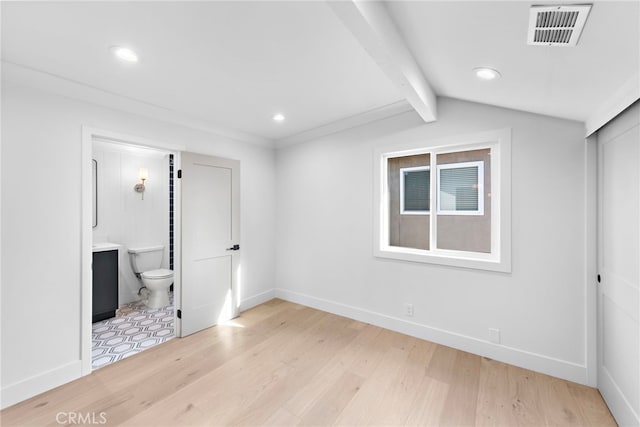 unfurnished bedroom featuring light wood finished floors, ensuite bath, visible vents, and baseboards