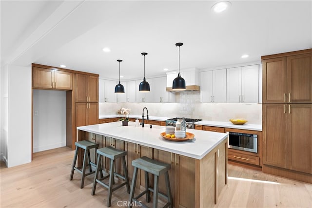 kitchen with light wood-type flooring, brown cabinetry, tasteful backsplash, and light countertops