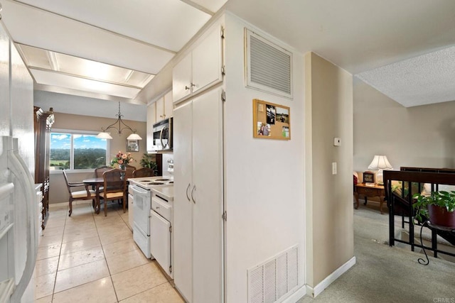 kitchen with white range with electric cooktop, visible vents, baseboards, white cabinets, and stainless steel microwave