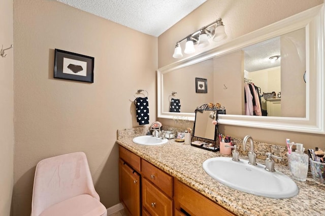 bathroom featuring a textured ceiling, double vanity, a sink, and toilet