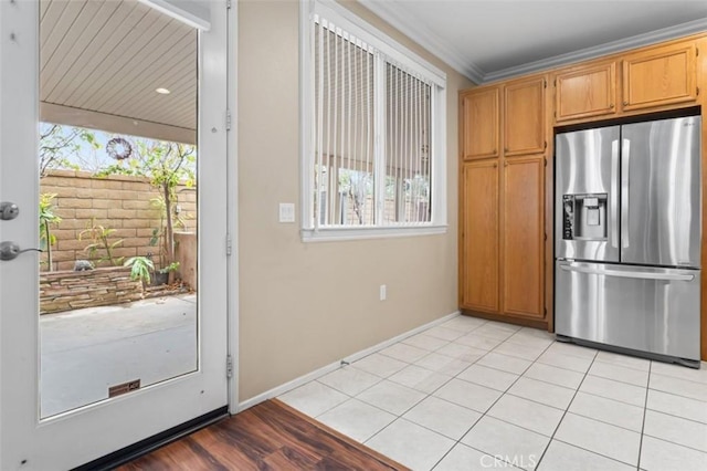 kitchen featuring light tile patterned floors, baseboards, stainless steel fridge, and crown molding