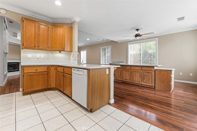 kitchen with visible vents, a sink, a peninsula, white dishwasher, and ceiling fan