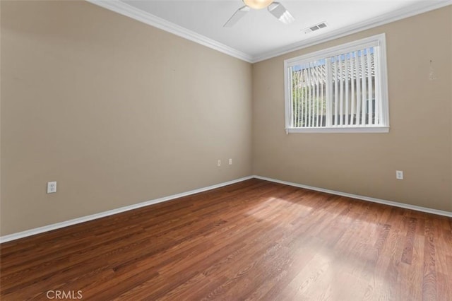 unfurnished room with visible vents, baseboards, wood finished floors, and crown molding