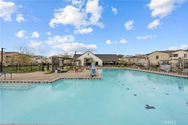 community pool with a patio, fence, and a residential view