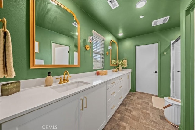 bathroom featuring a stall shower, stone finish flooring, visible vents, and vanity