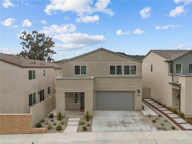 view of front facade with driveway, fence, an attached garage, and stucco siding