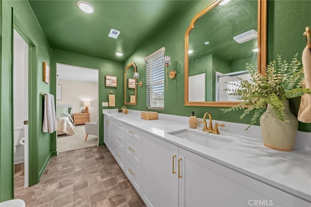 ensuite bathroom featuring double vanity, connected bathroom, toilet, and a sink