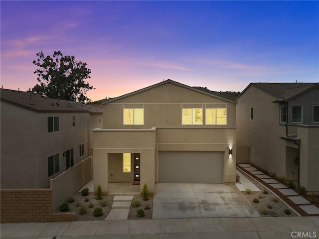 view of front of home featuring an attached garage, concrete driveway, and stucco siding