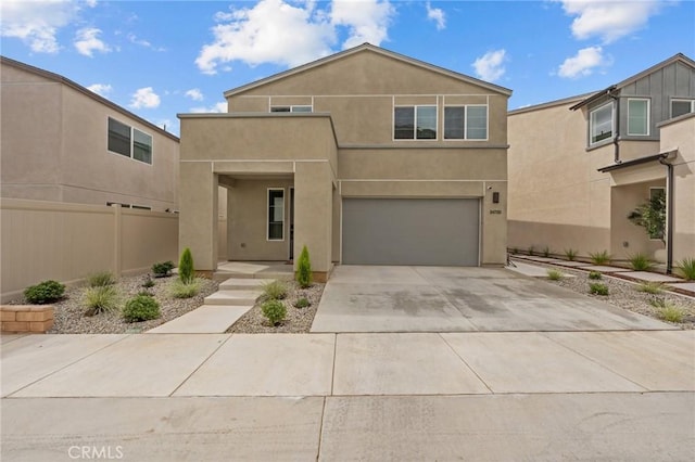 view of front of property with concrete driveway, fence, an attached garage, and stucco siding