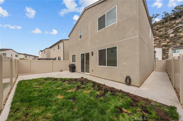 rear view of house featuring a lawn, a patio area, a fenced backyard, and stucco siding