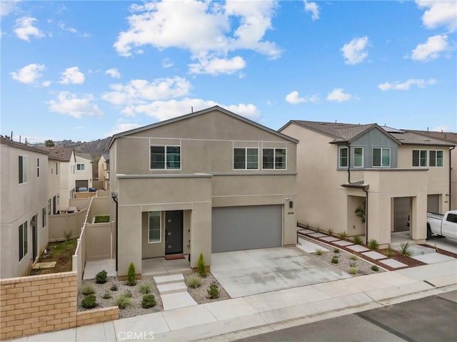 view of front facade featuring a garage, concrete driveway, fence, and stucco siding