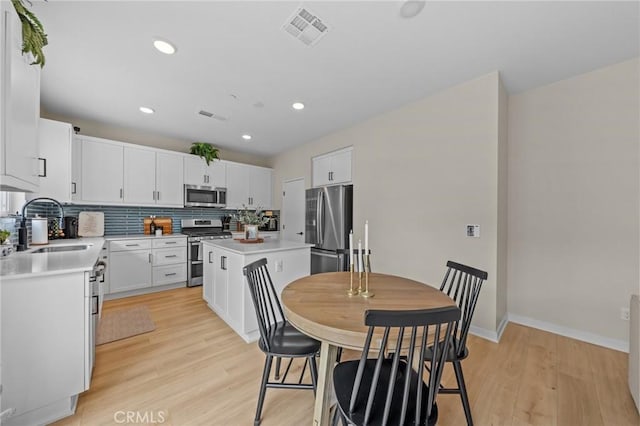 34720 Mustang Ln, Fallbrook, CA 92028 - kitchen featuring appliances with stainless steel finishes, light wood-type flooring, tasteful backsplash, light countertops, and white cabinets