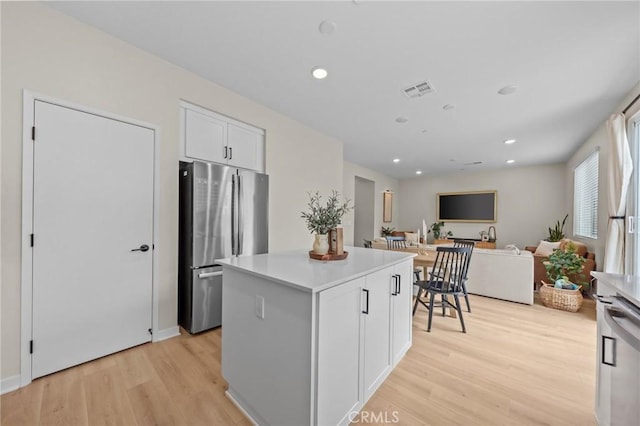 kitchen with light wood finished floors, a center island, white cabinetry, and freestanding refrigerator