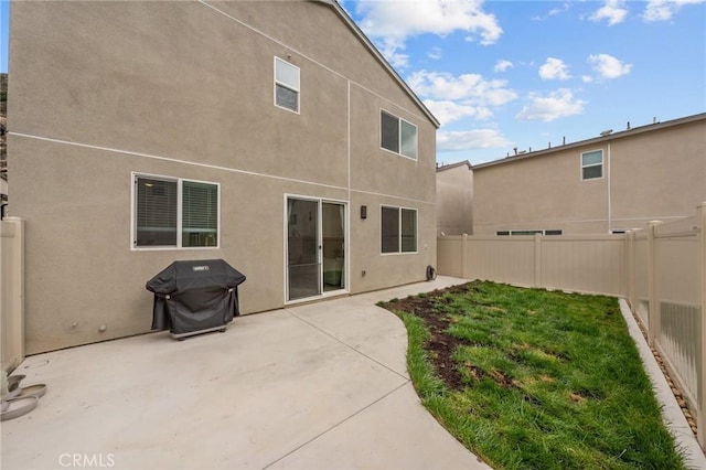 rear view of property featuring a patio area, a fenced backyard, a lawn, and stucco siding