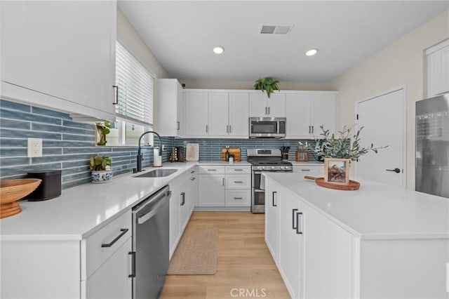 kitchen featuring stainless steel appliances, a sink, visible vents, white cabinetry, and light countertops