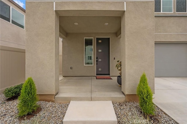 doorway to property featuring an attached garage and stucco siding