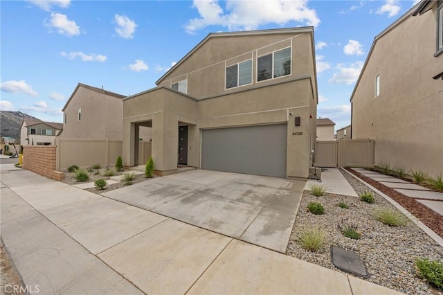 view of front facade featuring driveway, fence, an attached garage, and stucco siding