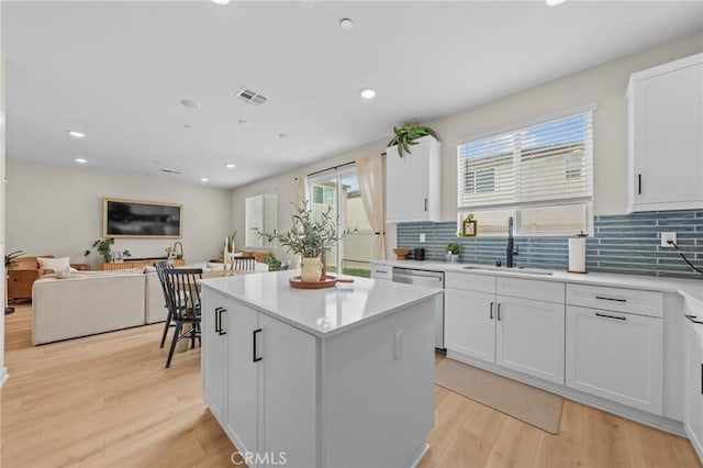 kitchen featuring light wood finished floors, visible vents, dishwasher, a center island, and a sink