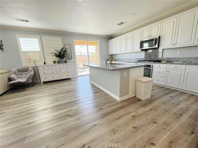 kitchen with light wood-type flooring, visible vents, appliances with stainless steel finishes, and crown molding