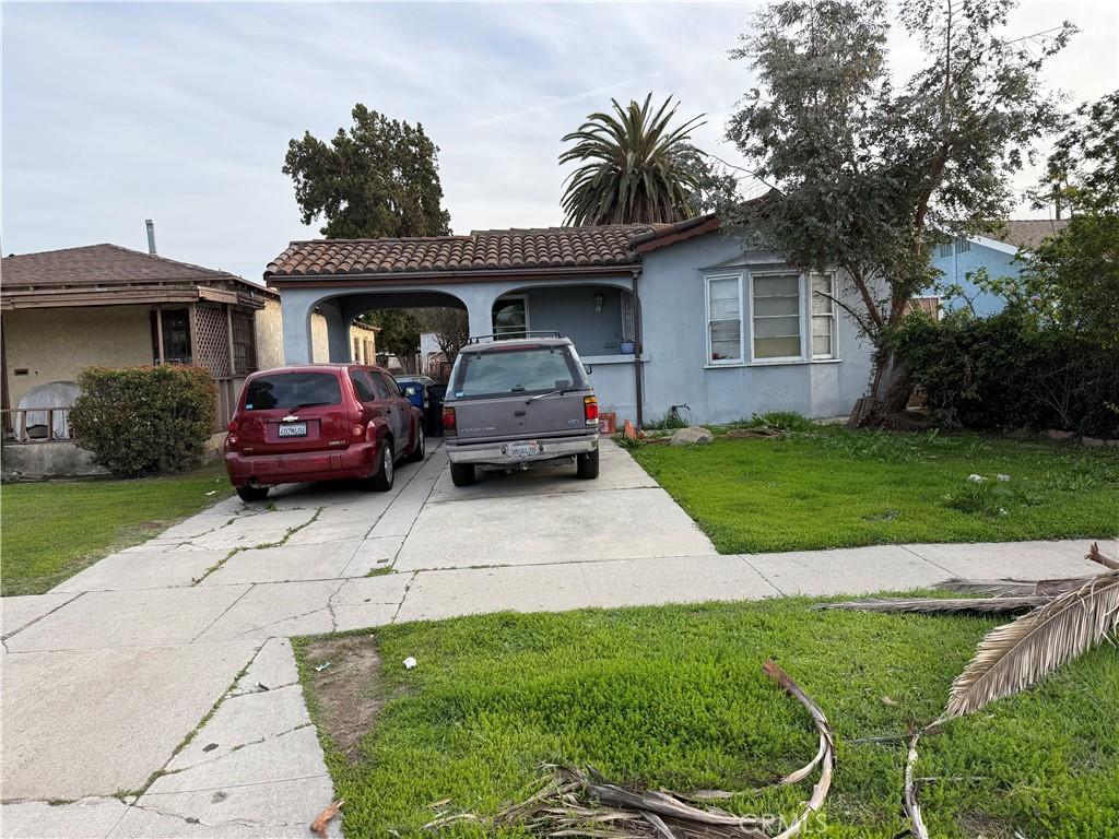 view of front of home featuring a tile roof, driveway, a front lawn, and stucco siding