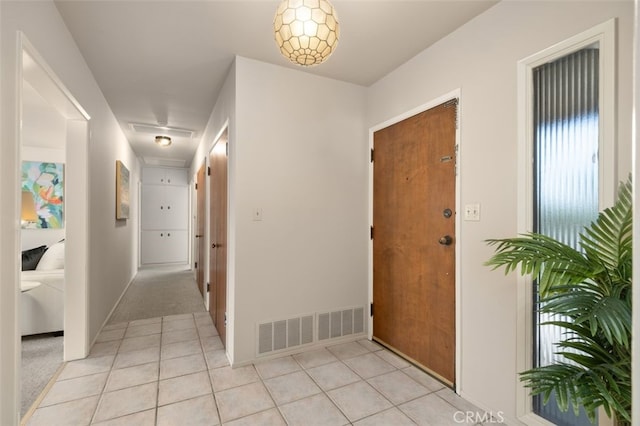 corridor featuring light tile patterned floors, visible vents, and baseboards