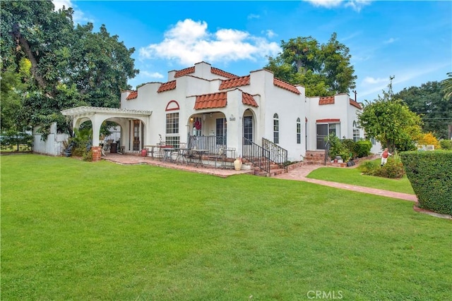 back of house with a tile roof, a lawn, a pergola, and stucco siding