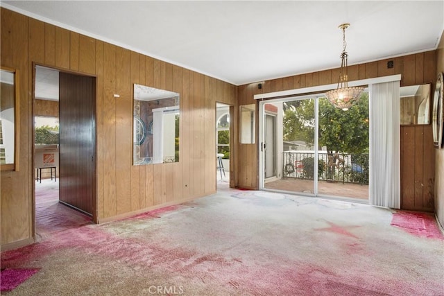 carpeted spare room with wood walls and baseboards