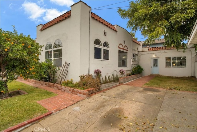 view of front of home featuring stucco siding, a front yard, and a tiled roof