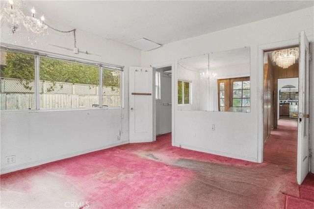 empty room featuring a chandelier and carpet