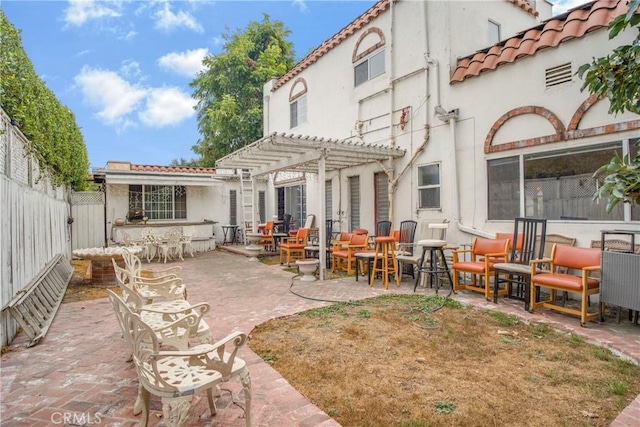 back of property with stucco siding, a pergola, a patio, fence, and a tiled roof