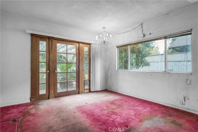 spare room with a chandelier, carpet, and a textured wall