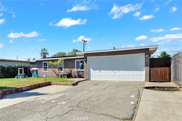 ranch-style house featuring a garage, concrete driveway, fence, a front yard, and stucco siding