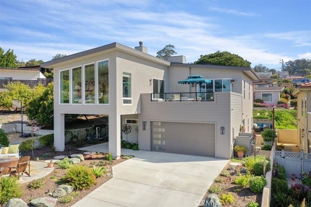 view of front of house with a chimney, stucco siding, an attached garage, fence, and driveway