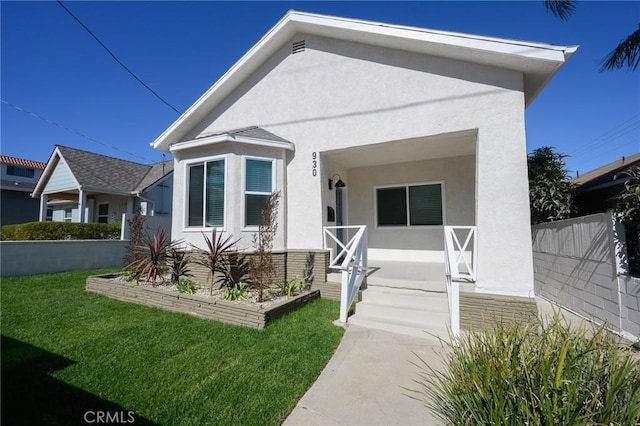 view of front of property featuring a front yard, fence, and stucco siding