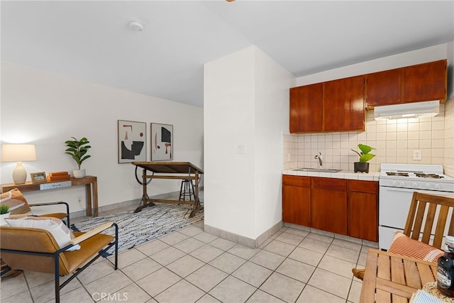 kitchen with tasteful backsplash, white gas range oven, tile countertops, under cabinet range hood, and a sink