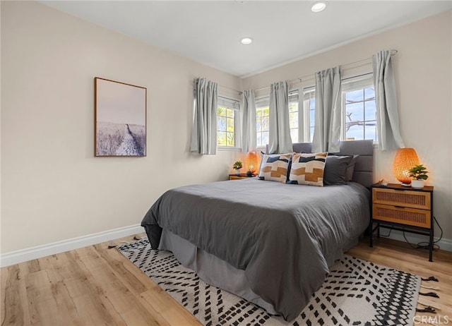 bedroom featuring multiple windows, wood finished floors, and baseboards