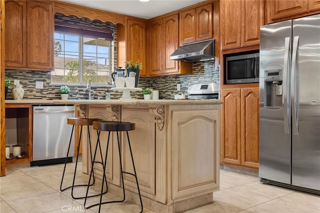 kitchen with appliances with stainless steel finishes, light countertops, under cabinet range hood, and light tile patterned flooring