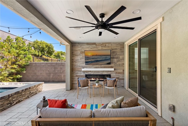 view of patio featuring a ceiling fan, outdoor dining space, fence, and an outdoor living space with a fireplace