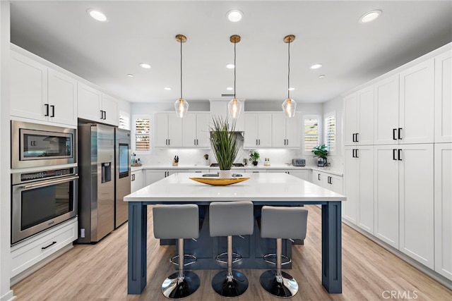 kitchen featuring light countertops, appliances with stainless steel finishes, white cabinets, and a center island