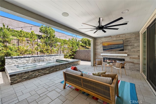 view of patio / terrace featuring a ceiling fan, a fenced backyard, and an outdoor living space with a fireplace