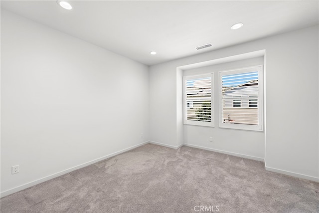 carpeted empty room with baseboards, visible vents, and recessed lighting