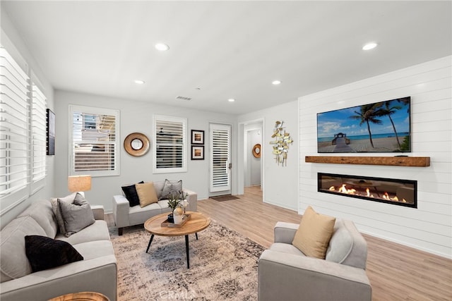 living area featuring recessed lighting, visible vents, wood finished floors, and a glass covered fireplace