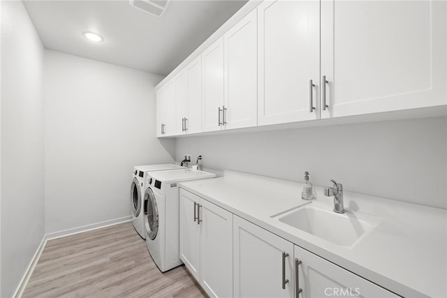 laundry room featuring a sink, visible vents, independent washer and dryer, cabinet space, and light wood finished floors