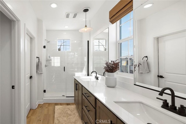 full bath with double vanity, a sink, visible vents, and a shower stall