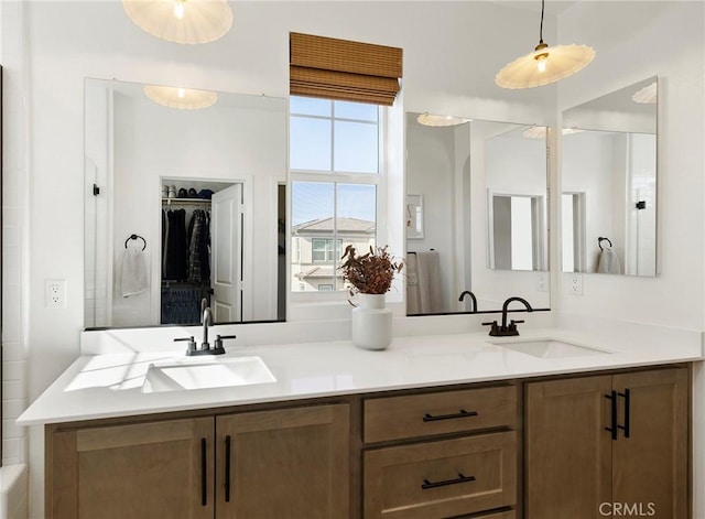 bathroom with double vanity, a spacious closet, and a sink