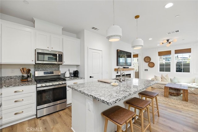 kitchen with appliances with stainless steel finishes, open floor plan, visible vents, and white cabinets