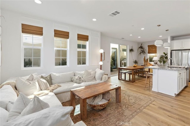 living area featuring light wood finished floors, visible vents, and recessed lighting