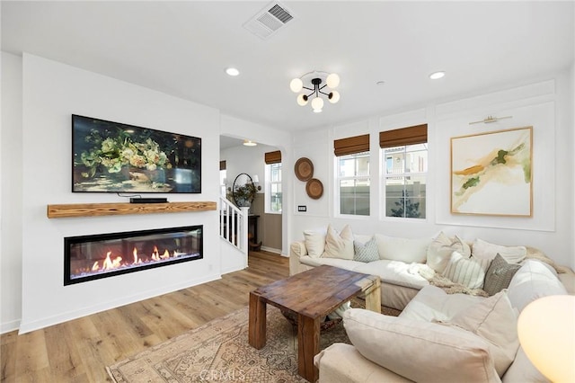 living area featuring a glass covered fireplace, wood finished floors, visible vents, and recessed lighting