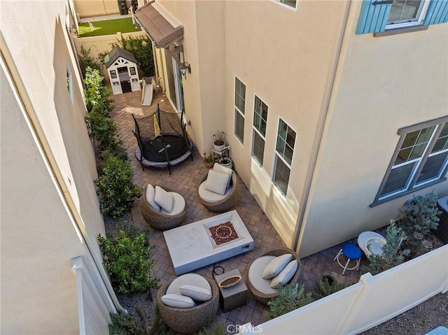 exterior space with a patio area, fence, a fire pit, and stucco siding