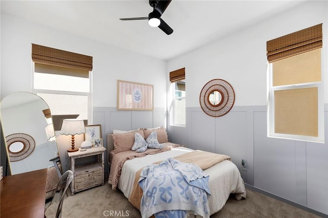 bedroom with wainscoting, carpet, a ceiling fan, and a decorative wall